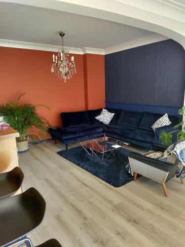 a living room with a black couch and orange walls at LifeinLiege in Liège