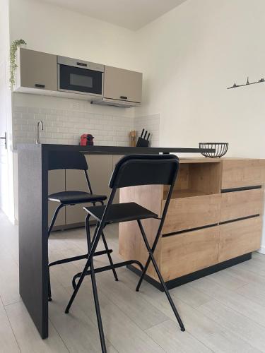 une cuisine avec un comptoir noir et deux chaises dans l'établissement Studio à Cormeilles-en-Parisis, à Cormeilles-en-Parisis