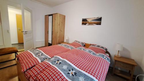 a bedroom with a bed with a red and white blanket at Appartement de vacances Les Jardins in Saint-Imier