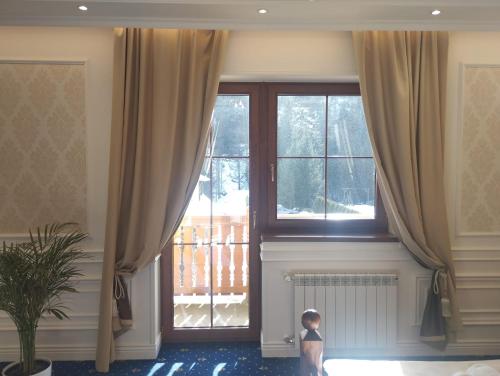 a child standing in front of a window with curtains at Boutique Hotel Budzak in Ždiar