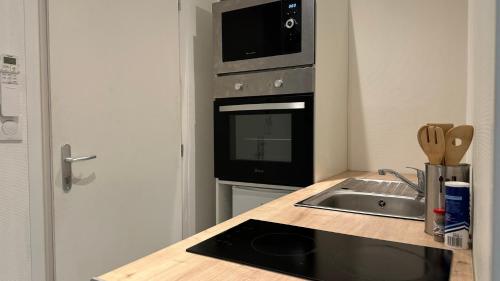 une cuisine avec un évier et un micro-ondes dans l'établissement Le Petit Loire, à Nevers