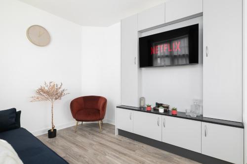 a living room with a bed and a tv on a wall at Modern Flat with Parking, 5 Mins to Tube in Kenton