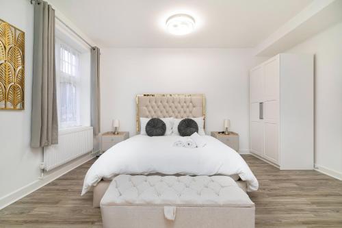 a white bedroom with a large bed and two windows at Modern Flat with Parking, 5 Mins to Tube in Kenton