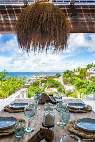 a table with wine glasses and a view of the ocean at Villa neuve à Lurin avec vue mer sunset à proximité de Gustavia in Gustavia