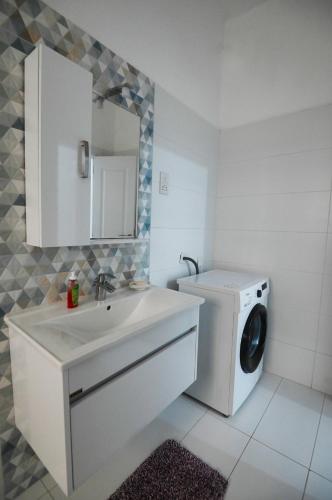 a white bathroom with a washing machine and a washer at Sunset Court Self Catering Sea View Apartment in Għajnsielem