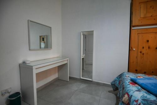 a bedroom with a desk and a mirror and a bed at Sunset Court Self Catering Sea View Apartment in Għajnsielem