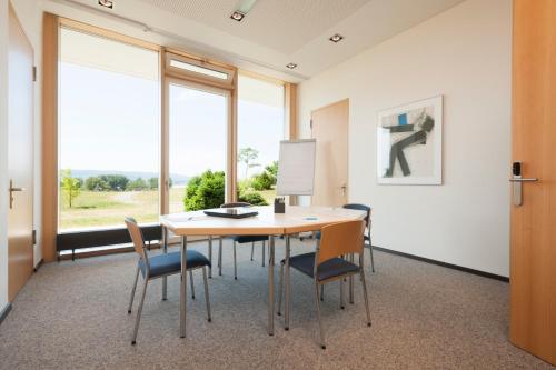 a conference room with a table and chairs and a large window at Hotel St Elisabeth in Allensbach