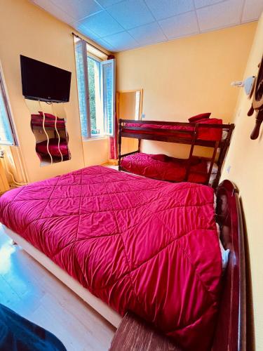 une chambre avec un lit avec une couette rouge dans l'établissement F1 Tulipe, à La Bourboule