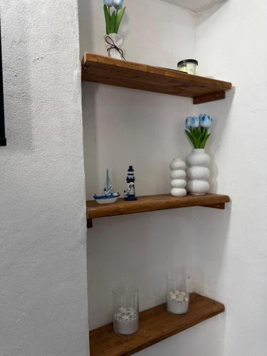 a wall with wooden shelves with flowers and vases at Framari in Vernazza