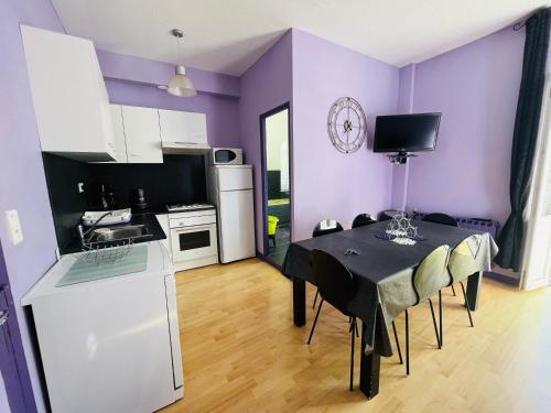 - une cuisine avec des murs violets, une table et des chaises dans l'établissement F2 Pavot, à La Bourboule