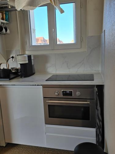 une cuisine avec une cuisinière et une fenêtre dans l'établissement Appartement Deauville hyper centre, à Deauville