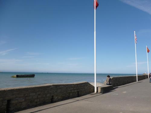 una persona seduta su un muro vicino all'oceano di Studio De La Mer ad Arromanches-les-Bains