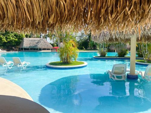 a swimming pool with chairs and a straw umbrella at Discover The Best Area of Coronado with Pool in Chame