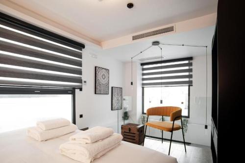 a bedroom with two beds and a chair and a window at SIGMA Suites Hotel in Thessaloniki