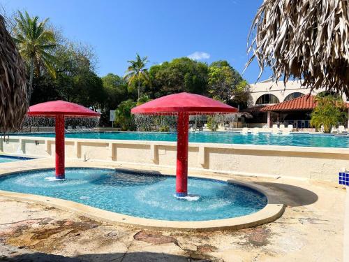 a pool with two red umbrellas in the water at Discover The Best Area of Coronado with Pool in Chame