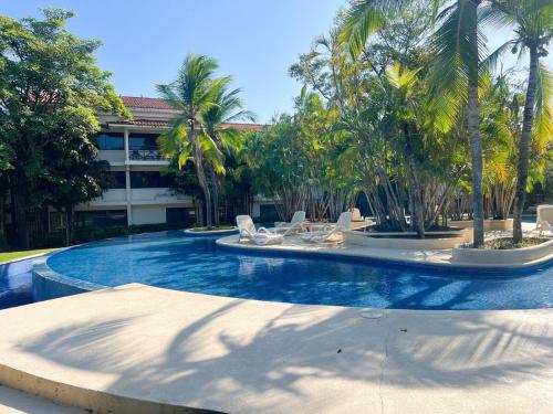 a swimming pool with chairs and palm trees in front of a building at Discover The Best Area of Coronado with Pool in Chame