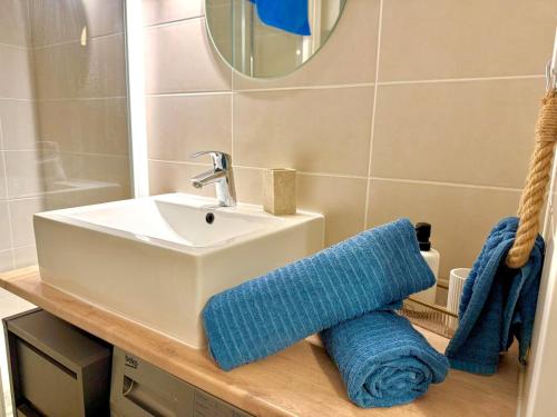 La salle de bains est pourvue d'un lavabo et d'une serviette bleue. dans l'établissement LE BLUE PACIFIC- 150m de la plage- Terrasse- Wifi, à La Grande Motte