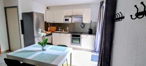 a kitchen with white cabinets and a table with flowers on it at Maison cosy au bord du canal, piscine et parking in Béziers
