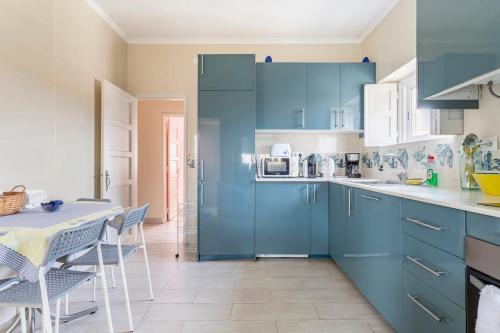 a kitchen with blue cabinets and a table with chairs at Casa dos Malmequeres in Sintra
