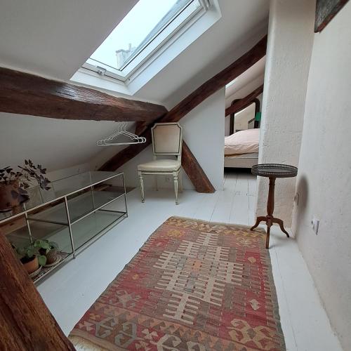 une chambre mansardée avec une lucarne, une chaise et un tapis dans l'établissement Unit 019 Ile Saint Louis duplex cosy flat 3 pax, à Paris