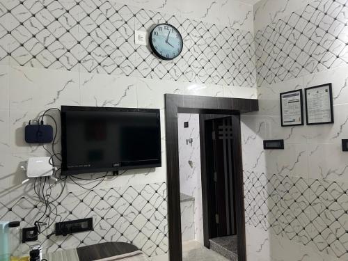 a wall with a tv and a clock on a wall at Rumi HomeStays in Bhubaneshwar