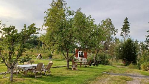 a picnic table and chairs in a yard with a house at Ferienwohnung Lövåsängen im Waldbauernhof, Årjäng in Årjäng