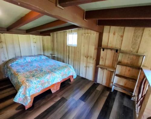 a bedroom with a bed in a room with wooden floors at Cabaña VIDA en Oncol in Valdivia