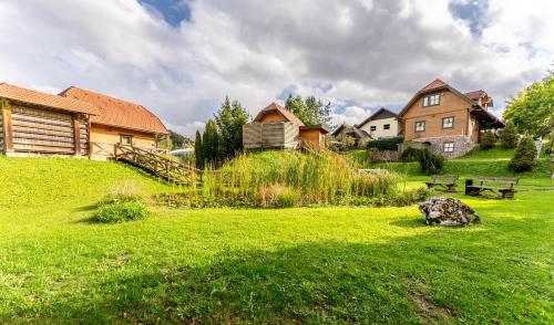 a green yard with houses and a bench in the grass at Korošec Apartments and Wellness Centre in Mozirje