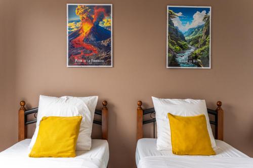 two beds in a room with two posters on the wall at Évasion Créole à Saint-André II - Parking - Clim in Saint-André
