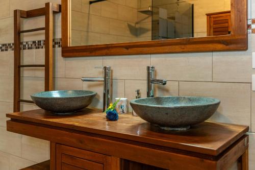two sinks sitting on a wooden counter in a bathroom at Évasion Créole à Saint-André II - Parking - Clim in Saint-André