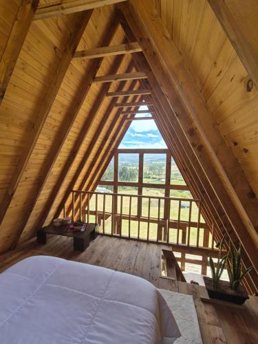 an attic bedroom with a bed and a large window at La Alejandría de Guasca in Guasca