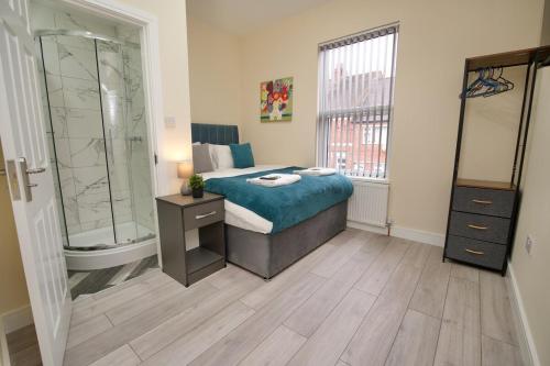 a bedroom with a bed and a shower and a sink at Monks Villa Fully Furnished Home Coventry in Coventry