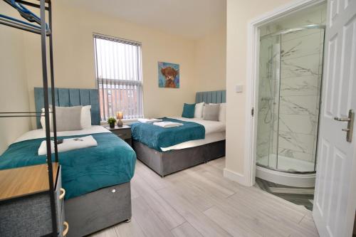 a hotel room with two beds and a shower at Monks Villa Fully Furnished Home Coventry in Coventry