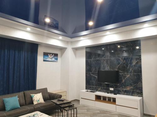 a living room with a couch and a flat screen tv at Pool House in Tbilisi City