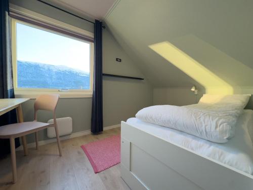 a bedroom with a bed and a desk and a window at Cozy and Central Loft in Tromsø in Tromsø