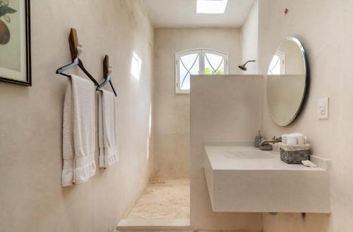 a white bathroom with a sink and a mirror at Casa Damiana in Mérida