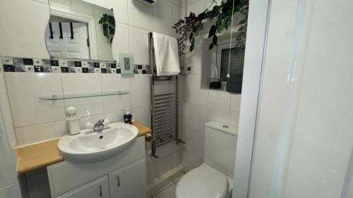 a white bathroom with a sink and a toilet at Bedsit Birmingham in Oldbury