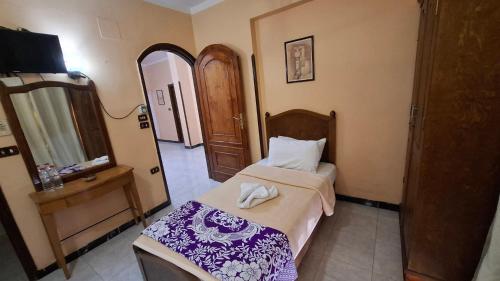 Un dormitorio pequeño con una cama y un espejo. en West Bank Guest House, en Luxor