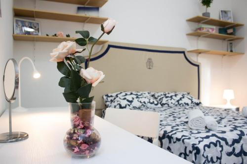 een vaas met roze rozen op een tafel in een slaapkamer bij Fra i Cavalieri e i Miracoli a 2 passi da tutto in Pisa