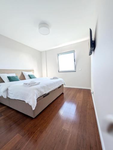 a white bedroom with a large bed and wooden floors at Seaview wonder apartment by Anna in Funchal