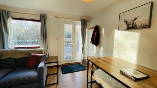 a living room with a couch and a table at Stylish Garden Flat Near Loch Ness in Drumnadrochit
