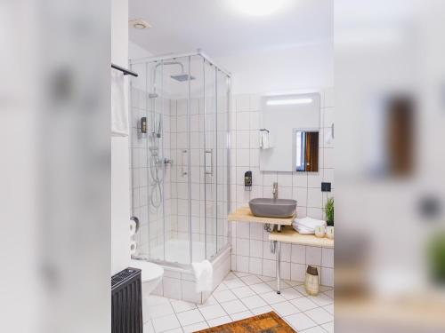 a white bathroom with a shower and a sink at Friedrich DAS BETT in Braunschweig