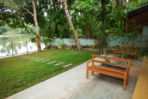 un banco sentado en una acera junto a un cuerpo de agua en Villa Sansun - Riverside Escape, en Weligama