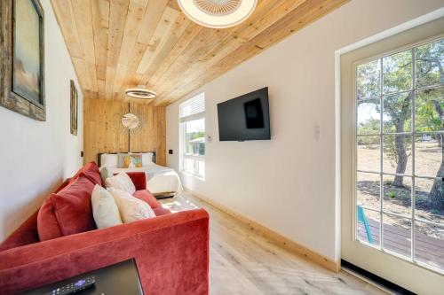 a living room with a red couch and a tv at Modern Hill Country Container in Spicewood