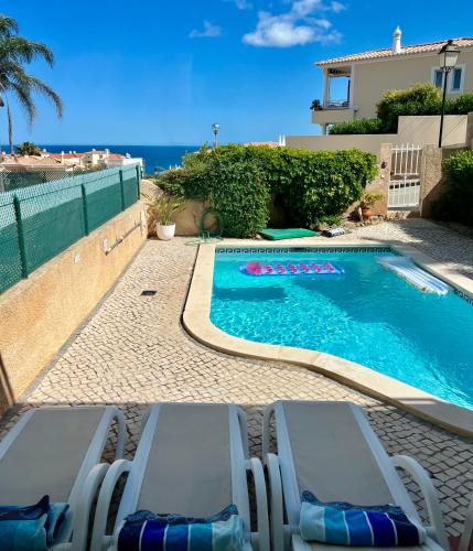 a swimming pool with chaise lounge chairs next to a house at OCEAN VIEW VILLA BELAMAR in Luz