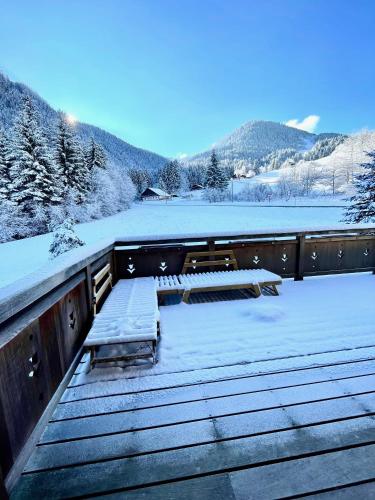 une terrasse en bois avec une table de pique-nique dans la neige dans l'établissement Chalet Les Oursons, à Bonnevaux