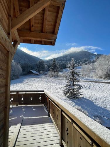 une terrasse en bois avec de la neige au sol dans l'établissement Chalet Les Oursons, à Bonnevaux
