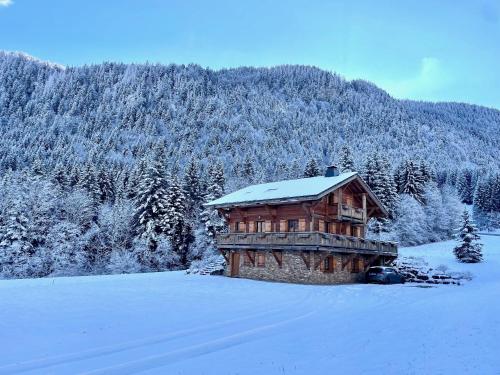 une cabane en rondins avec de la neige au-dessus dans l'établissement Chalet Les Oursons, à Bonnevaux
