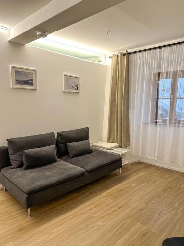 a couch in a living room with a window at Design Stadthaus Apartment mit privatem Zugang in Hallein