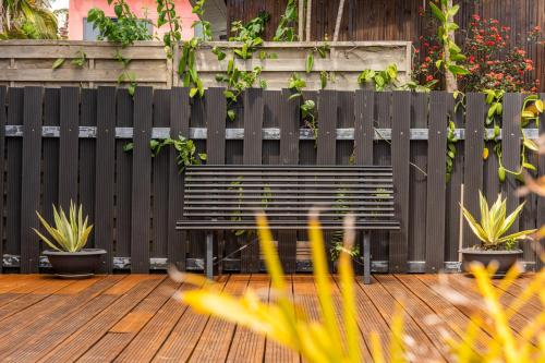 a black bench on a wooden deck with plants at Évasion Créole à Saint-André II - Parking - Clim in Saint-André